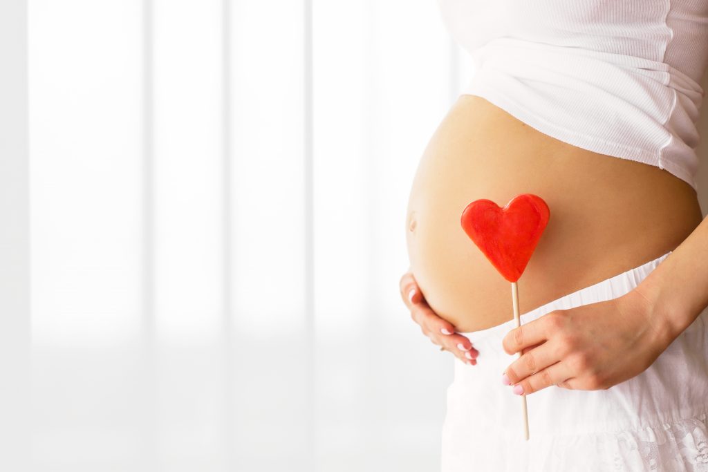 Add a theme to your pregnancy memory book progress photos, like holding a heart for February.