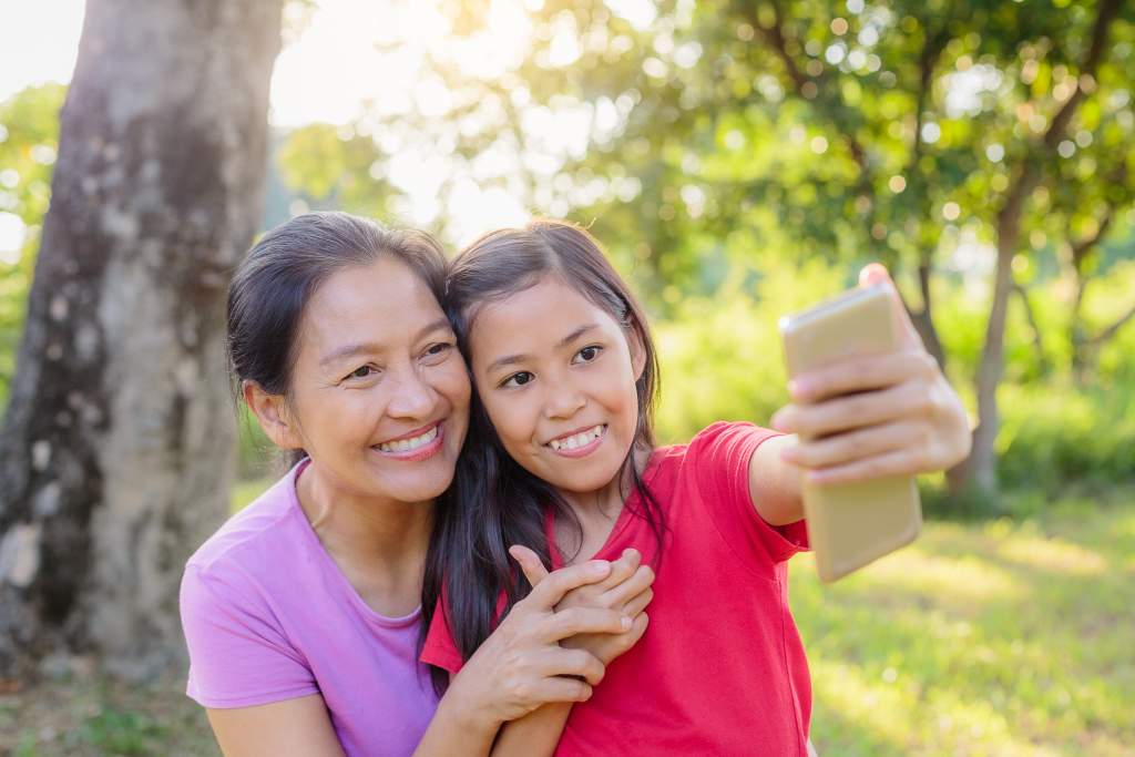 Young girl uses the iPhone 11 camera lenses to take selfie with her grandmother.