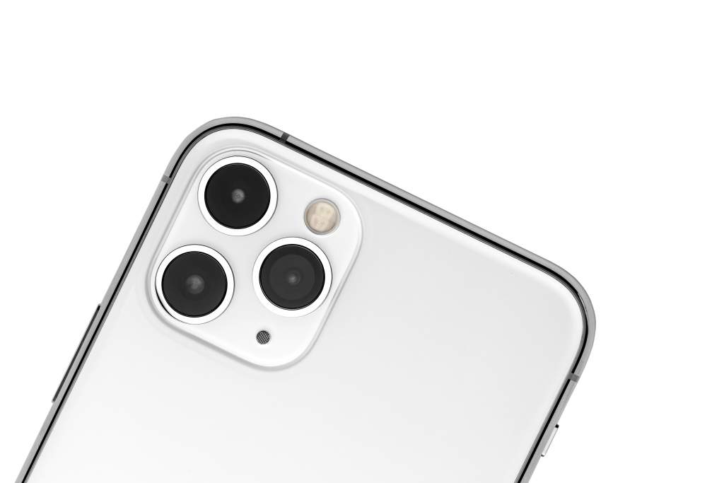 A close-up of a white iPhone 11 and its iPhone camera lenses on white background.