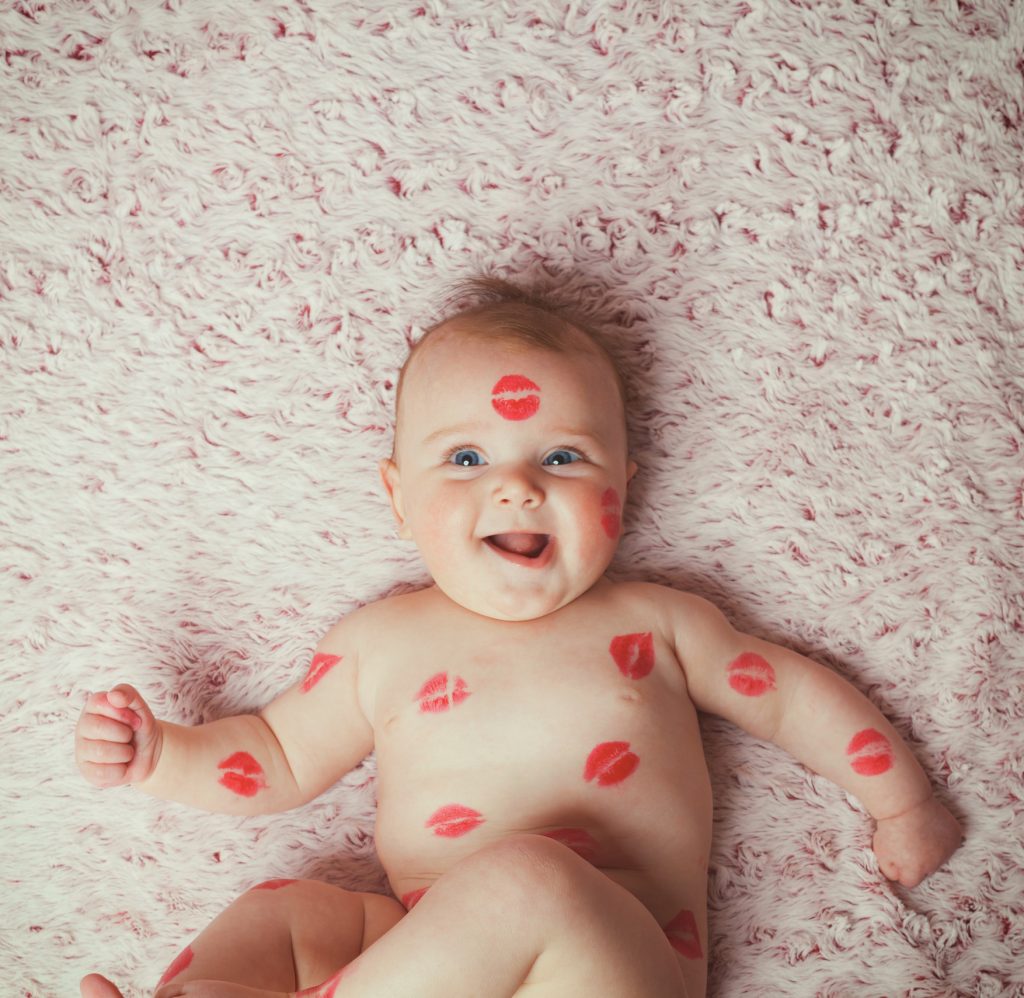 Newborn baby girl on the soft blanket filled kisses made with the lipstick.